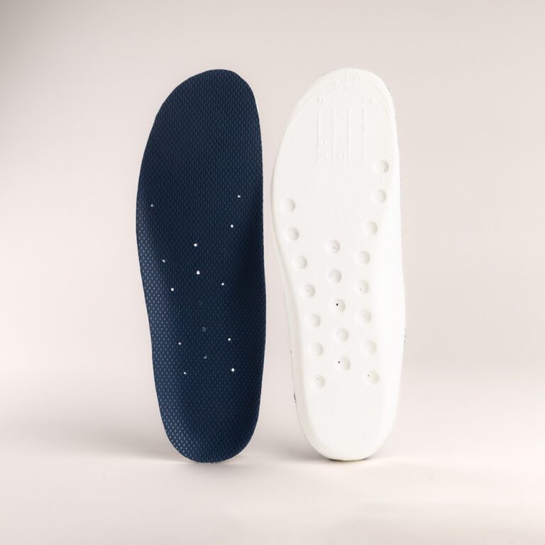 A pair of Skellerup Earthtec Orthotic innersoles is displayed against a neutral background. The left insole is dark blue with small perforations, while the right one is white and features various raised circular bumps, offering comfort and support.
