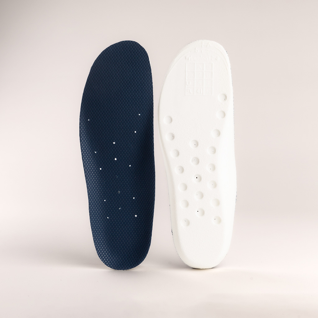 A pair of Skellerup Earthtec Orthotic innersoles is displayed against a neutral background. The left insole is dark blue with small perforations, while the right one is white and features various raised circular bumps, offering comfort and support.